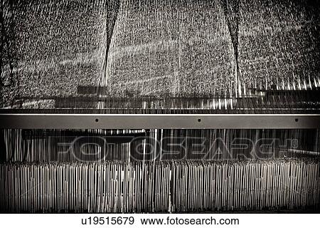 Stock Photo - Close up view of Jacquard loom with pattern formed by linen and cotton threads attached to heddle, high key monochrome image, Umbria, Italy. Fotosearch