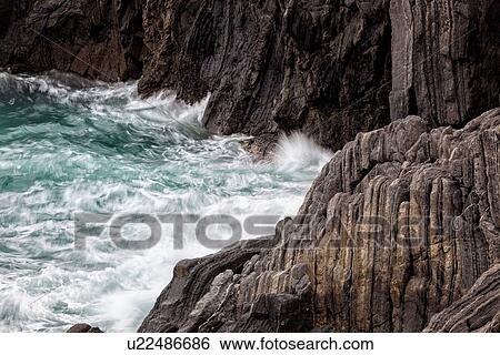 Stock Photograph - Detail of heavy seas smashing against rocks, with motion blur, Cinque Terre, Italy. Fotosearch