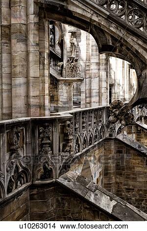 Picture - Detail of Milan Duomo rooftop: series of rooftop flying buttresses, elaborate stone carving, desaturated view, Milan Italy,. Fotosearch