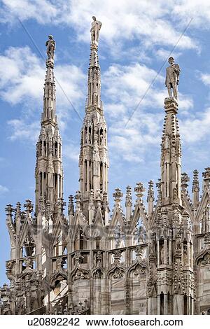 Stock Image - Detail of Milan Duomo rooftop: series of rooftop pinnacles and flying buttresses, elaborate stone carving, against sky, Milan Italy. Fotosearch