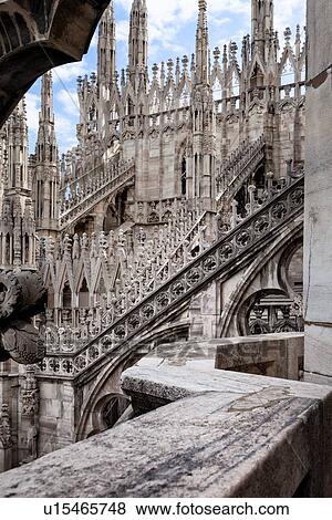 Stock Photo - Detail of Milan Duomo rooftop: series of rooftop pinnacles and flying buttresses, elaborate stone carving, against sky, Milan Italy. Fotosearch