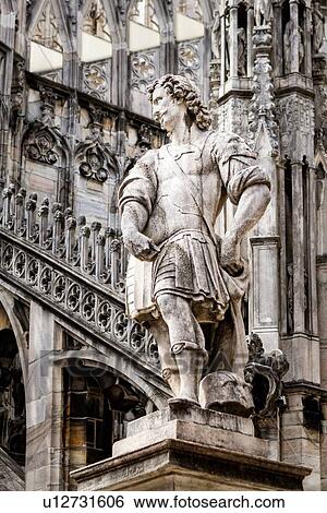 Detail of Milan Duomo rooftop: statue of cavalier soldier with rooftop pinnacles and flying buttresses beyond, elaborate stone carving, Milan Italy View Large Photo Image Stock Photograph - Detail of Milan Duomo rooftop: statue of cavalier soldier with rooftop pinnacles and flying buttresses beyond, elaborate stone carving, Milan Italy. Fotosearch