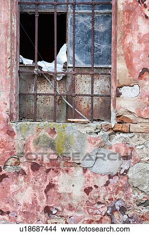 Picture - Detail of old derelict warehouse: crumbling pink and red stucco wall, broken window with rusty metal grate, Emilia Romagna, Italy. Fotosearch