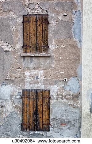 Detail of old stucco house with crumbling facade, ancient wooden shutters over windows, typical style, Emilia Romagna, Italy View Large Photo Image Picture - Detail of old stucco house with crumbling facade, ancient wooden shutters over windows, typical style, Emilia Romagna, Italy. Fotosearch