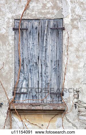 Stock Image - Detail of old stucco house with crumbling facade, ancient wooden shutter over window, typical style, Emilia Romagna, Italy. Fotosearch