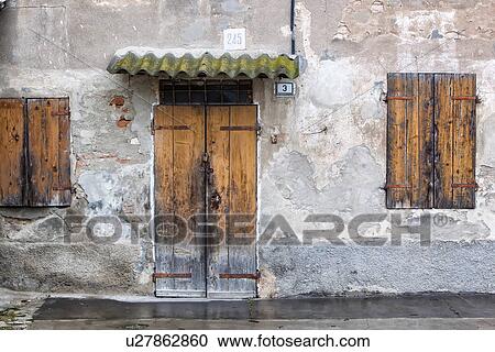 Detail of old stucco house with crumbling facade, ancient wooden shutters over windows and door, corrugated moss-covered rain cover overhead, typical style, Emilia Romagna, Italy View Large Photo Image Stock Image - Detail of old stucco house with crumbling facade, ancient wooden shutters over windows and door, corrugated moss-covered rain cover overhead, typical style, Emilia Romagna, Italy. Fotosearch