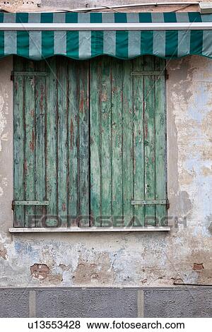 Detail of old stucco house with crumbling facade, green wooden shutter over window with green and white awning, all paint peeling, typical style, Emilia Romagna, Italy View Large Photo Image Stock Photo - Detail of old stucco house with crumbling facade, green wooden shutter over window with green and white awning, all paint peeling, typical style, Emilia Romagna, Italy. Fotosearch