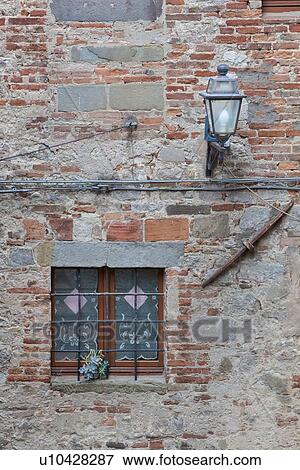 Detail of red brick wall of house, with small window with traditional metal grate and white lace curtain, medieval village, Umbria, Italy View Large Photo Image Stock Photo - Detail of red brick wall of house, with small window with traditional metal grate and white lace curtain, medieval village, Umbria, Italy. Fotosearch