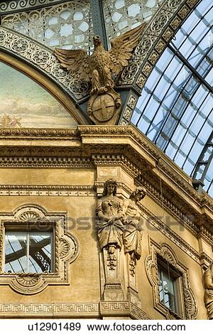 Gallerica Vittorio Emanuele: close up detail view of central mall area ceiling, glass and cast iron arched roof with stone carving statues, Milan Italy View Large Photo Image Stock Photo - Gallerica Vittorio Emanuele: close up detail view of central mall area ceiling, glass and cast iron arched roof with stone carving statues, Milan Italy. Fotosearch