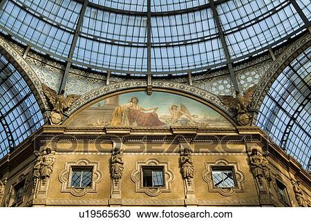 Stock Image - Gallerica Vittorio Emanuele: detail view of central mall area ceiling, glass and cast iron arched roof and central dome with stone carving decoration, Milan Italy. Fotosearch