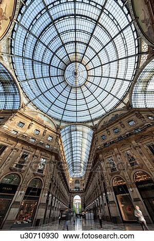 Gallerica Vittorio Emanuele: detail view of central mall area, people shopping, glass and cast iron arched roof and central dome with stone carving decoration, mosaic flooring, Milan Italy View Large Photo Image Stock Image - Gallerica Vittorio Emanuele: detail view of central mall area, people shopping, glass and cast iron arched roof and central dome with stone carving decoration, mosaic flooring, Milan Italy. Fotosearch