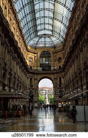 Stock Photo - Gallerica Vittorio Emanuele: detail view of central mall area, people shopping, glass and cast iron arched roof with stone carving decoration, mosaic flooring, Milan Italy. Fotosearch