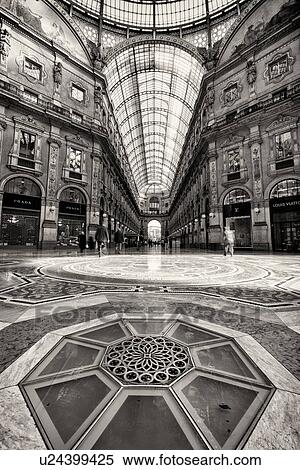 Gallerica Vittorio Emanuele: detail view of central mall area, people shopping, glass and cast iron arched roof with stone carving decoration, mosaic flooring, monochrome view, Milan Italy View Large Photo Image Stock Photography - Gallerica Vittorio Emanuele: detail view of central mall area, people shopping, glass and cast iron arched roof with stone carving decoration, mosaic flooring, monochrome view, Milan Italy. Fotosearch