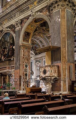 Picture - Genoa Centro Storico: Church of San Gesu detail view across pews with single woman, of richly decorated pulpit, frescoed ceiling and lavish Baroque decoration, Genova, Italy. Fotosearch