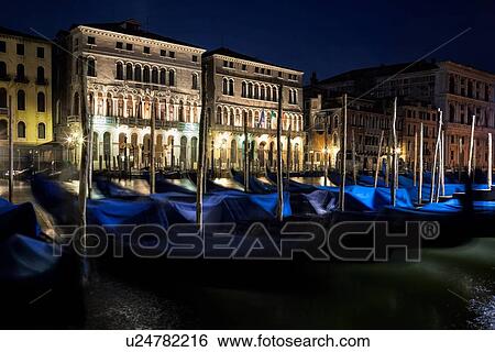 Stock Photograph - Gondolas rocking on a tranquil Grand canal at nightime with view of ornate Palazzi beyond, Venice Italy. Fotosearch