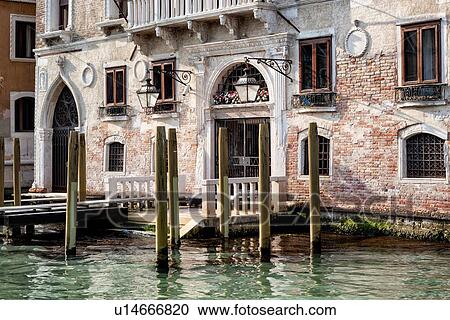 Stock Image - Grand Canal, detail of ornately decorated palazzi, wooden poles for mooring gondolas, late afternoon golden light, Venice, Italy. Fotosearch