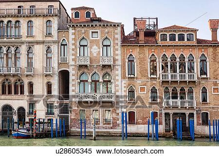 Stock Photography - Grand Canal, detail of ornately decorated palazzi, brightly coloured poles for mooring gondolas, late afternoon golden light, Venice, Italy. Fotosearch