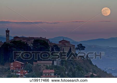 Stock Photograph - Hilltop medieval town of MonteCastello di Vibio with full moon rising above church and campanile, hills beyond, Umbria, Italy. Fotosearch
