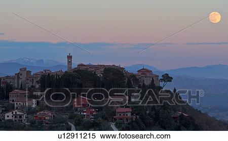 Stock Photography - Hilltop medieval town of MonteCastello di Vibio with full moon rising above church and campanile, snowcapped mountains and hills beyond, Umbria, Italy. Fotosearch