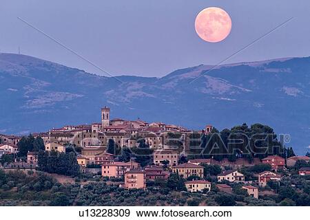 Huge pink full moon peeping over hills and cloud beyond medieval hilltop town of MonteCastello di Vibio at twilight, with blue sky, Umbria, Italy View Large Photo Image Stock Photo - Huge pink full moon peeping over hills and cloud beyond medieval hilltop town of MonteCastello di Vibio at twilight, with blue sky, Umbria, Italy. Fotosearch