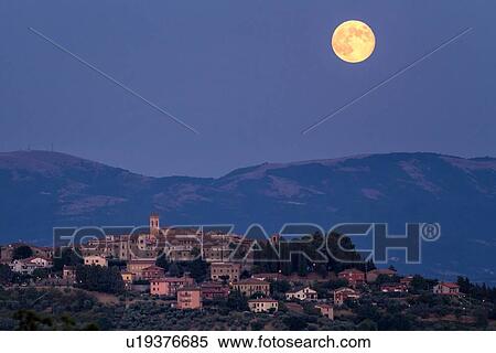 Huge pink full moon peeping over hills and cloud beyond medieval hilltop town of MonteCastello di Vibio at twilight, with blue sky, Umbria, Italy View Large Photo Image Stock Photography - Huge pink full moon peeping over hills and cloud beyond medieval hilltop town of MonteCastello di Vibio at twilight, with blue sky, Umbria, Italy. Fotosearch
