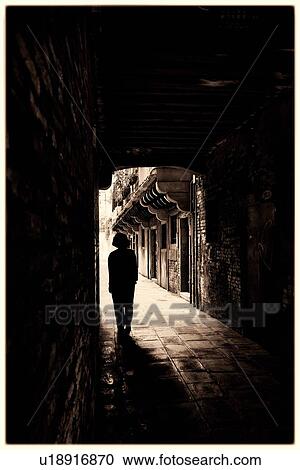 Into the light: silhouette of single woman walking under dark arch of portico towards open piazza wlined by wooden porticoed medieval houses, Venice, Italy View Large Photo Image Stock Image - Into the light: silhouette of single woman walking under dark arch of portico towards open piazza wlined by wooden porticoed medieval houses, Venice, Italy. Fotosearch