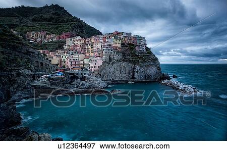 Manarola at sunset: village and fishing harbour at dusk, sweeping clouds with storm approaching, Cinque Terre, Liguria, Italy View Large Photo Image Stock Photo - Manarola at sunset: village and fishing harbour at dusk, sweeping clouds with storm approaching, Cinque Terre, Liguria, Italy. Fotosearch