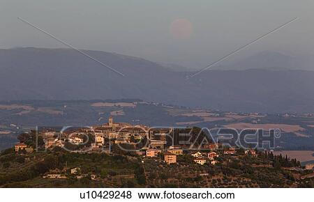 Stock Photo - Medieval hilltop town of MonteCastello di Vibio at sunset, as the pale full moon rises over the hills beyond the Tiber valley, Umbria, Italy. Fotosearch