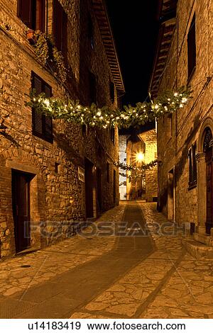 Stock Photo - Medieval hilltop town of MonteCastello di Vibio: street at night, with night lights, and Christmas garlands strung between the old stone houses, Umbria, Italy. Fotosearch