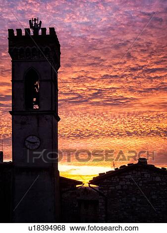 Medieval hilltop town of MonteCastello di Vibio: piazza at dusk, with close up of campanile and old stone buildings silhouetted against amazing ornage purple pink sky, Umbria, Italy View Large Photo Image Stock Photo - Medieval hilltop town of MonteCastello di Vibio: piazza at dusk, with close up of campanile and old stone buildings silhouetted against amazing ornage purple pink sky, Umbria, Italy. Fotosearch