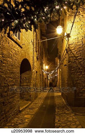 Medieval hilltop town of MonteCastello di Vibio: street at night, with night lights, and Christmas garlands strung between the old stone houses, motion blur of people, Umbria, Italy View Large Photo Image Stock Photo - Medieval hilltop town of MonteCastello di Vibio: street at night, with night lights, and Christmas garlands strung between the old stone houses, motion blur of people, Umbria, Italy. Fotosearch