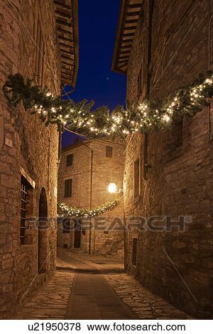 Medieval hilltop town of MonteCastello di Vibio: street at dusk, with night lights, and Christmas garlands strung between the old stone houses, motion blur of people, Umbria, Italy View Large Photo Image Stock Photo - Medieval hilltop town of MonteCastello di Vibio: street at dusk, with night lights, and Christmas garlands strung between the old stone houses, motion blur of people, Umbria, Italy. Fotosearch