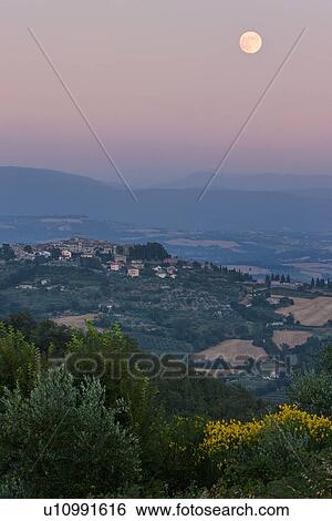 Medieval hilltop town of MonteCastello di Vibio at sunset, as the pale full moon rises over the hills beyond the Tiber valley, Umbria, Italy View Large Photo Image Stock Photograph - Medieval hilltop town of MonteCastello di Vibio at sunset, as the pale full moon rises over the hills beyond the Tiber valley, Umbria, Italy. Fotosearch