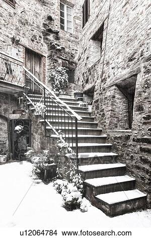 Picture - Medieval street - stone house and stairway entrance, covered with snow in early dawn light, desaturated view, MonteCastello di Vibio, Umbria, Italy. Fotosearch