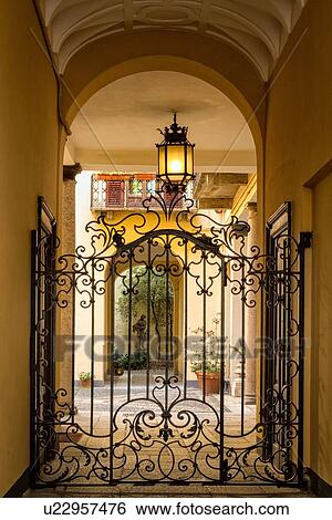 Milan Fashion District: palazzo entranceway with stucco arched ceiling, beautiful wrought iron gate and attractive courtyard beyond, Milan, Italy View Large Photo Image Stock Photograph - Milan Fashion District: palazzo entranceway with stucco arched ceiling, beautiful wrought iron gate and attractive courtyard beyond, Milan, Italy. Fotosearch