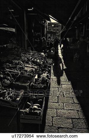 Picture - Narrow street in Historic Centre of Bologna, people shopping, dramatic light with shadows, monochrome image, Bologna, Italy. Fotosearch