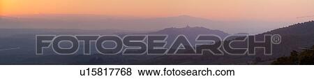 Panorama view of Tiber valley at sunrise with hills silhouetted purple by valley mist, with hilltop town of Todi and spire of San Fortunato outlined, gentle pink-orange sky, Umbria, Italy View Large Photo Image Stock Photo - Panorama view of Tiber valley at sunrise with hills silhouetted purple by valley mist, with hilltop town of Todi and spire of San Fortunato outlined, gentle pink-orange sky, Umbria, Italy. Fotosearch
