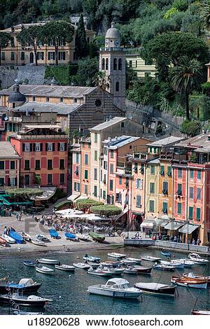 Portofino aerial view of harbour with fishing boats and motor launches, brightly coloured apartment buildings, outdoor cafes, church and belltower beyond in lush greenery, Liguria, Italy View Large Photo Image Stock Photo - Portofino aerial view of harbour with fishing boats and motor launches, brightly coloured apartment buildings, outdoor cafes, church and belltower beyond in lush greenery, Liguria, Italy. Fotosearch