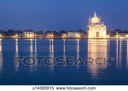 Stock Photography - Redentore church as seen at twilight with lights of the Giudecca, and blue calm water at dawn, Venice, Italy. Fotosearch