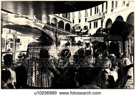 Stock Photo - Rialto Bridge reflections: monochrome image of passengers reflected in glass windows of ferry, Rialto bridge and gondolier framed beyond, Venice, Italy. Fotosearch