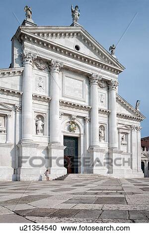 Stock Image - San Giorgio Maggiore facade, and white and stone paved piazza, lone woman on cell phone in front of church, Venice, Italy. Fotosearch
