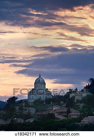 Stock Image - Santa Maria della Consolazione (Tempio) view at sunset with dramatic grey yellow clouds, Todi, Umbria, Italy. Fotosearch