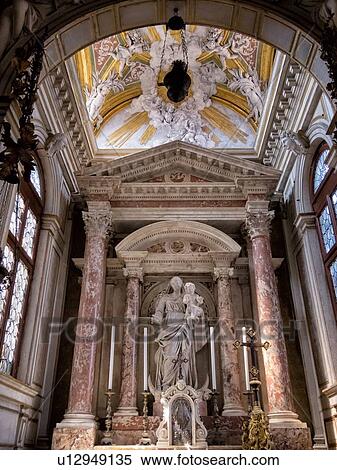 Stock Photography - Scuola Grande dei Carmini: chapel altar with red marble columns, intricate ceiling bas-relief stucco decorations framing marble statue of Virgin and Child, Venice, Italy. Fotosearch