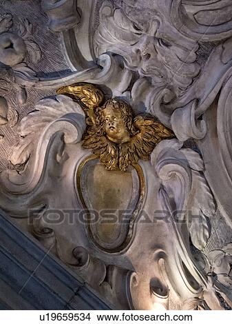 Scuola Grande dei Carmini: detail of ornate stucco garland decorations around gilded face and wings of putto, Venice, Italy View Large Photo Image Picture - Scuola Grande dei Carmini: detail of ornate stucco garland decorations around gilded face and wings of putto, Venice, Italy. Fotosearch