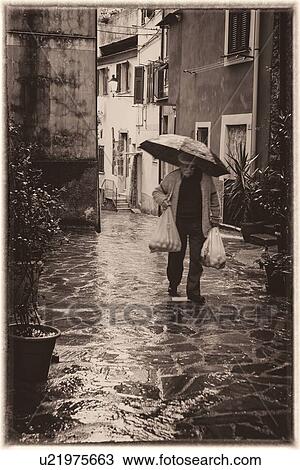 Single elderly gentleman carrying plastic bags of shopping and umbrella along wet street with houses in background, Monterosso al Mare, Cinque Terre, Liguria, Italy View Large Photo Image Stock Image - Single elderly gentleman carrying plastic bags of shopping and umbrella along wet street with houses in background, Monterosso al Mare, Cinque Terre, Liguria, Italy. Fotosearch