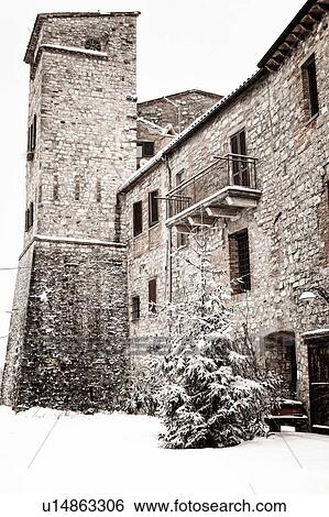 Stock Photograph - Snow-covered pathway around medieval town, stone houses with ancient tower, winter morning, MonteCastello di Vibio, Umbria, Italy. Fotosearch