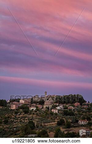 Stock Photography - Sunset view of medieval hilltop town of MonteCastello di Vibio. stone houses and belltower, olive groves on slope below, with pink and blue twilight sky, Umbria, Italy. Fotosearch