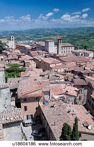 Stock Photograph - Todi: aerial view of red tiled rooftops, Palazzo del Populo, Duomo and Tiber valley beyond, on lovely spring morning, Umbria, Italy. Fotosearch