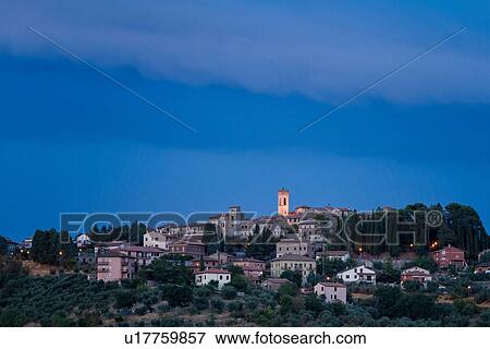 Stock Photo - Twilight view of medieval hilltop town of MonteCastello di Vibio. stone houses and belltower, olive groves on slope below, with pink and blue twilight sky, Umbria, Italy. Fotosearch