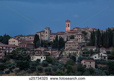 Stock Photography - Twilight view of medieval hilltop town of MonteCastello di Vibio. stone houses and belltower, olive groves on slope below, with pink and blue twilight sky, Umbria, Italy. Fotosearch